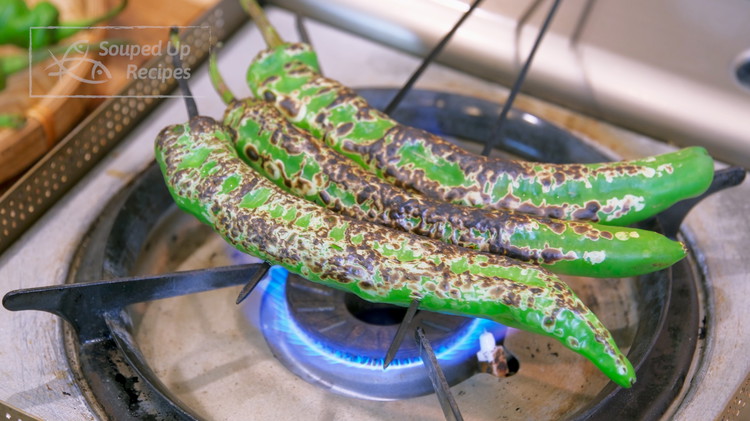 Image of While waiting, we can roast the chili peppers. Stick the chilies onto 2 skewers and roast them over open flame. You need about 2 minutes on each side, and the surface should be burned. If you don’t have a gas stove, you...