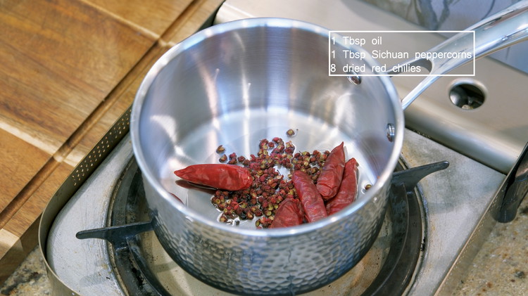 Image of While waiting, add a drizzle of oil to a saucepan along with 1 tbsp of Sichuan peppercorns and 1/4 cup of dried red chilies and stir over low heat for a few minutes.