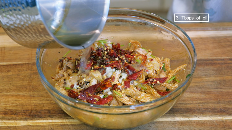 Image of Place the chicken into a big serving bowl. Add diced scallions and cilantro. Pour in the seasoning sauce. Sprinkle some roasted sesame seeds, the minced garlic, and the dao kou la jiao (chopped Sichuan peppercorns and chilies). Heat 3 tbsp of oil...