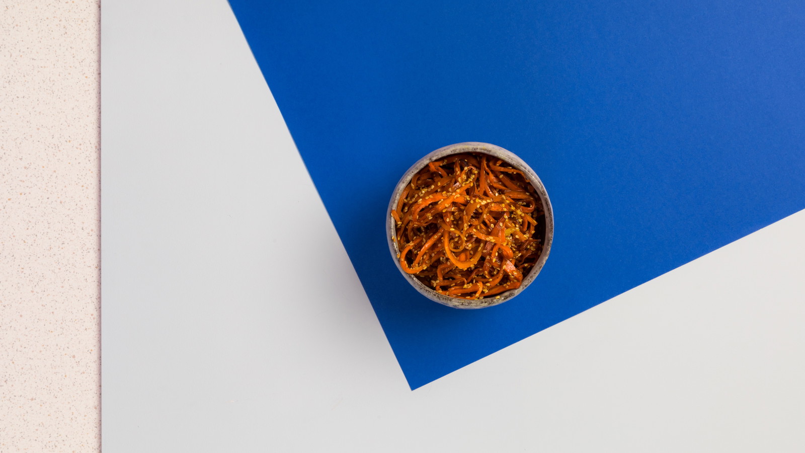 A vibrant bowl of shredded carrot, sesame seeds, chilli and honey.