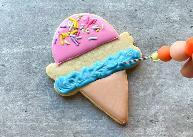 Image of Use a scribe tool or toothpick to gently move the blue icing around to create a nice ice cream texture. 