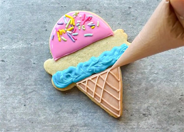 Image of Once your light brown cone icing has dried, you can pipe the waffle cone detail using light brown outline consistency icing. Be sure not to do this while the base icing is wet, as you will lose definition. 