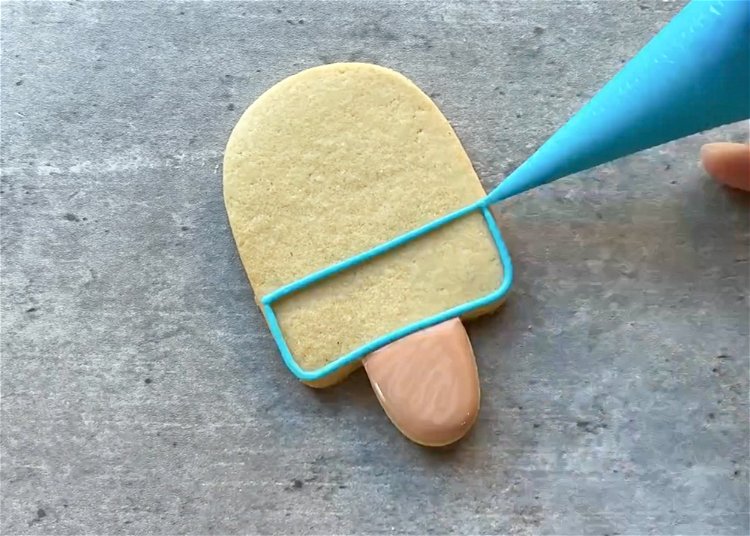 Image of Use light blue royal icing to outline the lower third of the popsicle. 