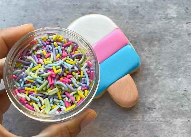 Image of While the white icing is still wet, add sprinkles to the top part of the popsicle. 