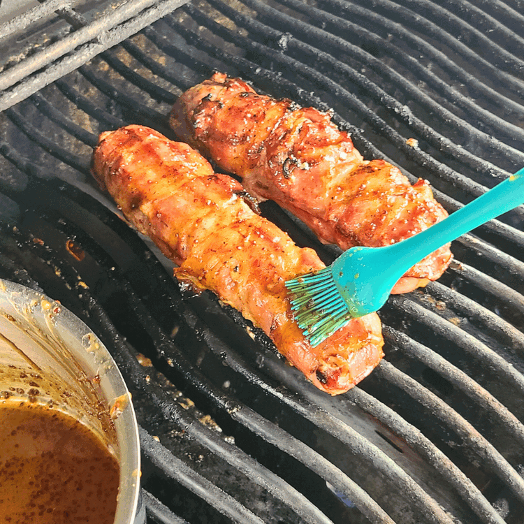 Image of Once the meat reaches 135°F, brush the bourbon glaze onto the wild boar tenderloins. Increase the temperature of the grill to medium-high.