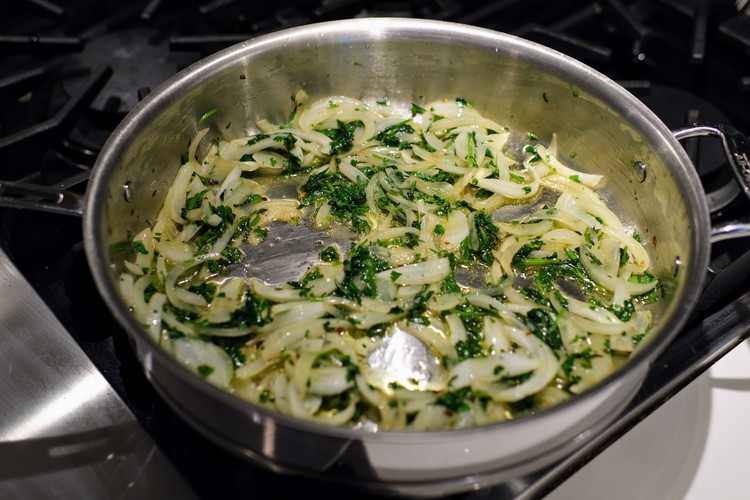 Image of Discard cilantro stems and roughly chop the upper part of the cilantro bunch. Reserve a very small amount of the leaves for plating.  Add most of the cilantro to pan and stir into onions.  Cook until onions start to soften.