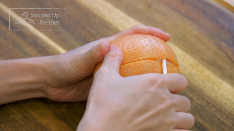 Image of While waiting, take the flesh out of a grapefruit. Use a pairing knife to score the grapefruit skin across the middle. Then, stick a chopstick underneath and wiggle it around to lose the peel. Do the same thing to the...