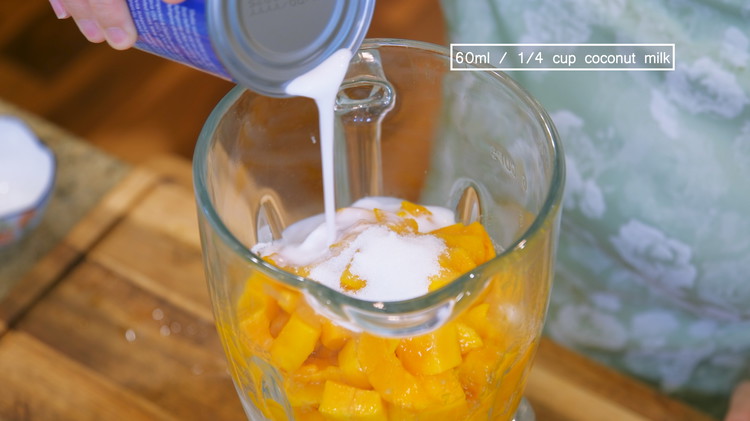 Image of Take the frozen evaporated milk out of the freezer and pop it into a big blender. Add 1/2 of the mango flesh, 3 Tbsps of sugar, and 1/4 cup into the blender (reserve 3/4 cup for later)