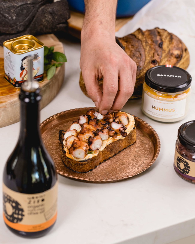 Image of slow-cooked octopus & hummus on toasted olive bread