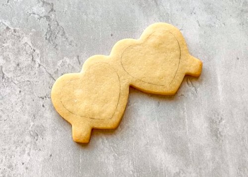 Image of Bake and cool cookies fully before decorating. Prepare royal icing in the following colors and consistencies:  Thick Flood Consistency: Black Pro tip: The black icing will darken with time. To prevent color bleed, where dark colors seep into each other, make your icing a dark grey color. As the icing dries on the cookie, the color will deepen to a deep charcoal color. Outline Consistency: Red Flood Consistency:  Red 