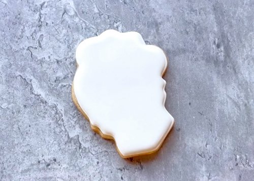 Image of Outline and flood the cookie with white royal icing. Wait at least 60 minutes, or until the base flood is fully dry and hardened before moving on to the next step. You can also flood your cookies the day before decorating to ensure that the icing has time to harden. 