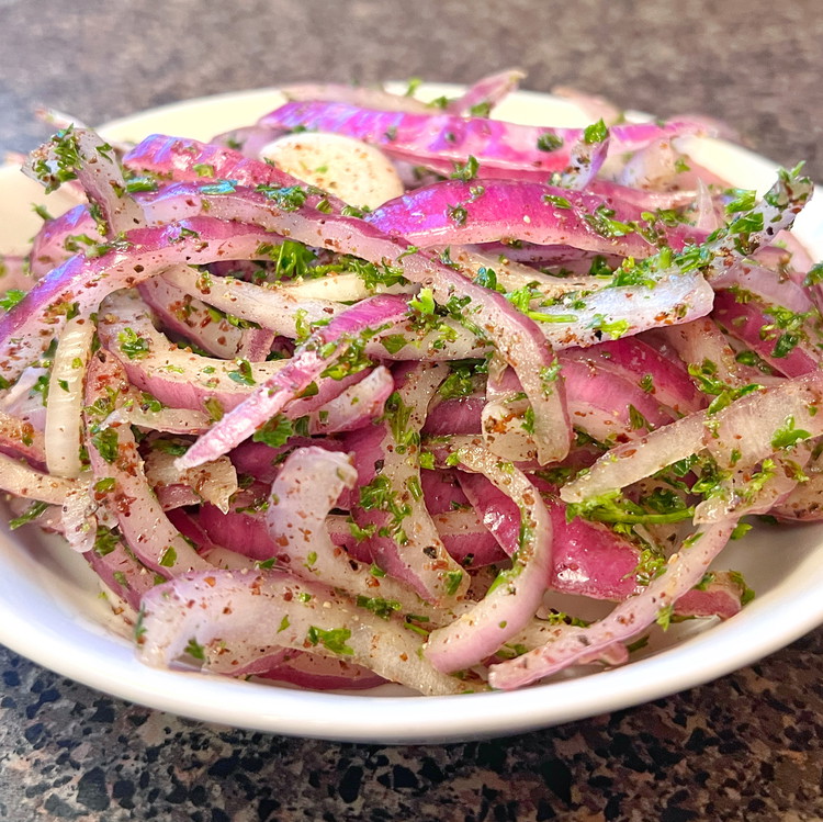 Image of Place the onion slices in a bowl, season with salt and squeeze them a few times with your fingers to extract some of the juice.