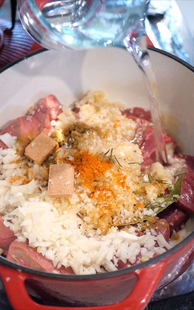 Image of Slice beef topside into chunks add to a heavy bottomed pot alongside water, blended aromatics and spices.