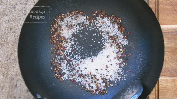 Image of Add the Sichuan peppercorns, salt, white, and black pepper in a wok and stir over low heat for 2-3 minutes. Remove everything from the wok and let them cool on the side.