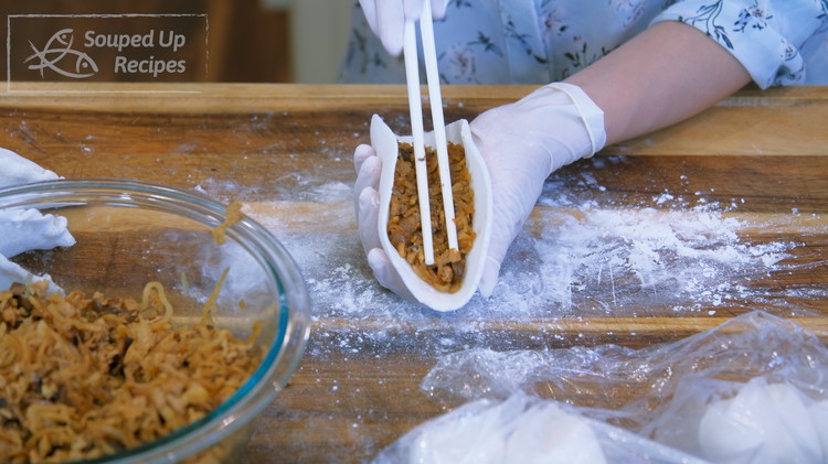 Image of Put some filling in the middle of the wrapper, about 50 grams. Use your chopsticks to carefully pack it tight.
