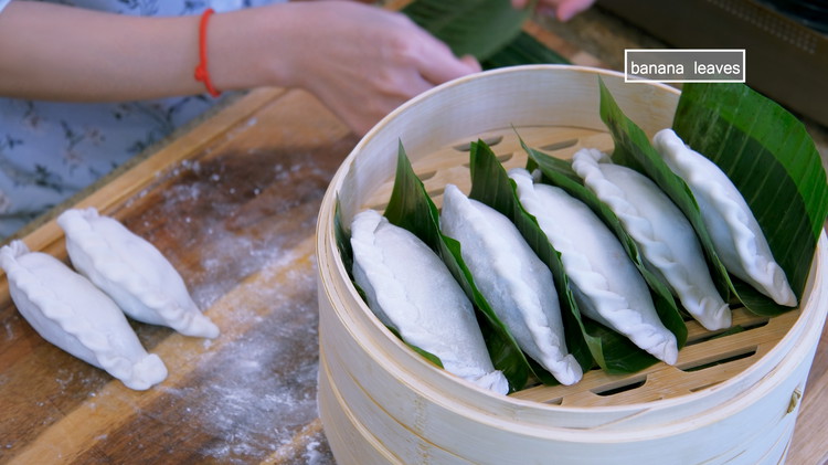 Image of Cut the banana leaves into rectangles and place them under the dumplings to prevent sticking.