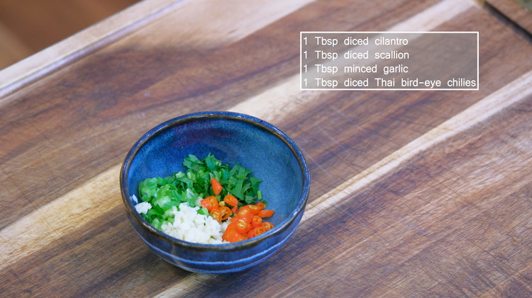 Image of In a heat-proof bowl, add diced cilantro, scallion, garlic, and Thai bird eye chilies. 