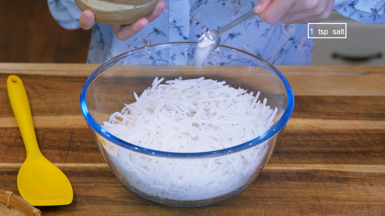 Image of Shred the radish using a vegetable grater. Toss the radish with 1 tsp of salt and let it sit for 20 minutes, giving the salt enough time to draw out some moisture. 