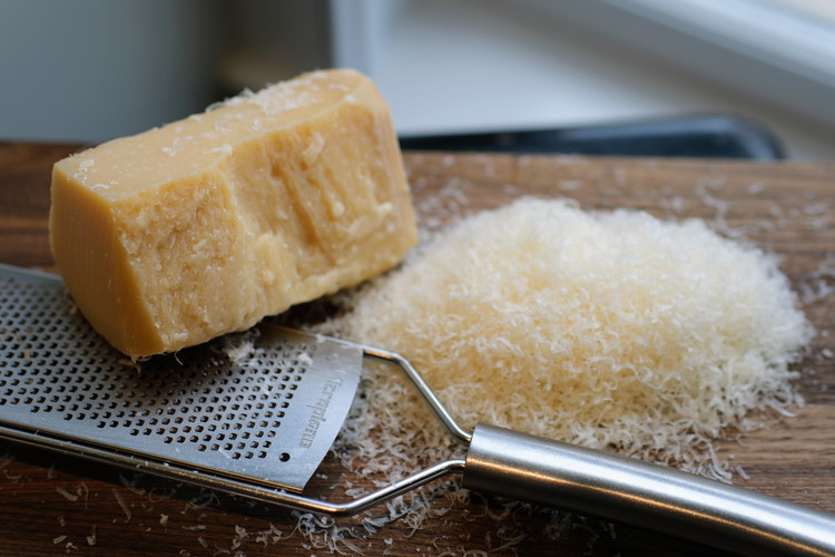 Image of Grate your parmesan.  Freshly grated works best because these fine strands ‘melt’ into the salad and coat the arugula leaves nicely without clumping.