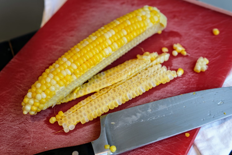 Image of Carefully slice the kernels from the corn cob. Doing so with the corn flat on a cutting board (as opposed to slicing down a standing corn cob) is the better option—slicing the standing corn cob tends to make the kernels...