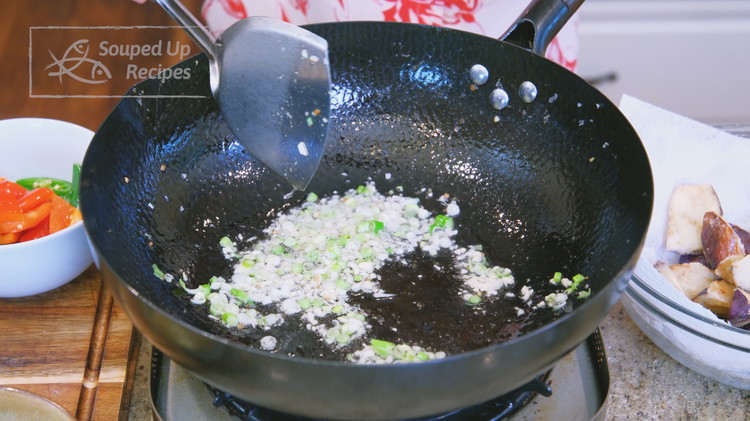 Image of Pour most of the oil out but leave 1.5 Tbsps in the wok. Add the diced garlic and the white part of the scallions, and sauté for 1 minute.