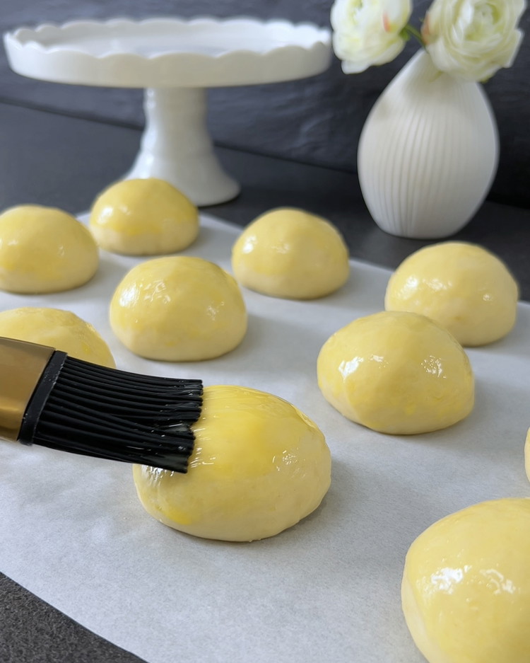 Image of Den Ofen auf 180°C vorheizen. Die Teigbälle mit verquirltem Eigelb bestreichen und im vorgeheizten Ofen etwa 15-20 Minuten backen, bis sie goldbraun sind.