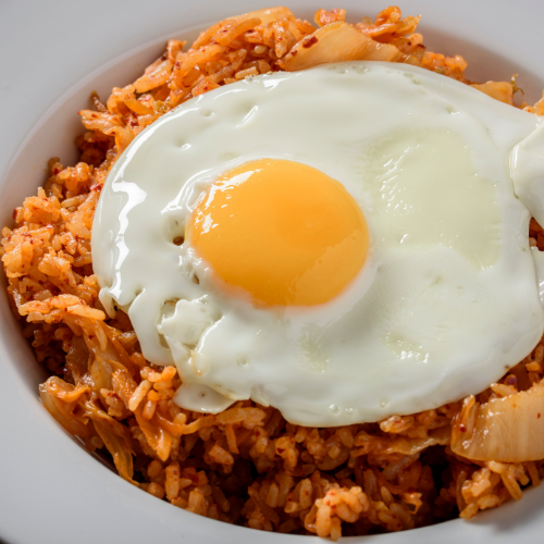 Image of Servieren:Den Kimchi Fried Rice auf Schalen verteilen. Mit einem Spiegelei, restlichen Frühlingszwiebeln und gerösteten Sesamsamen garnieren. Heiß servieren.