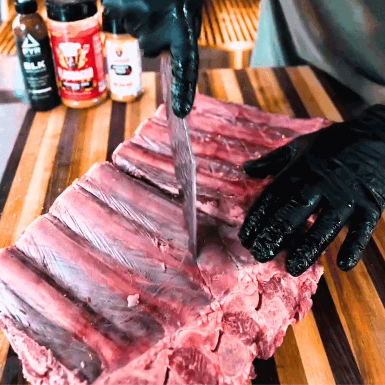 Image of Start by making shallow cuts across the membrane on the back of the ribs. This helps the seasoning penetrate while keeping things intact.