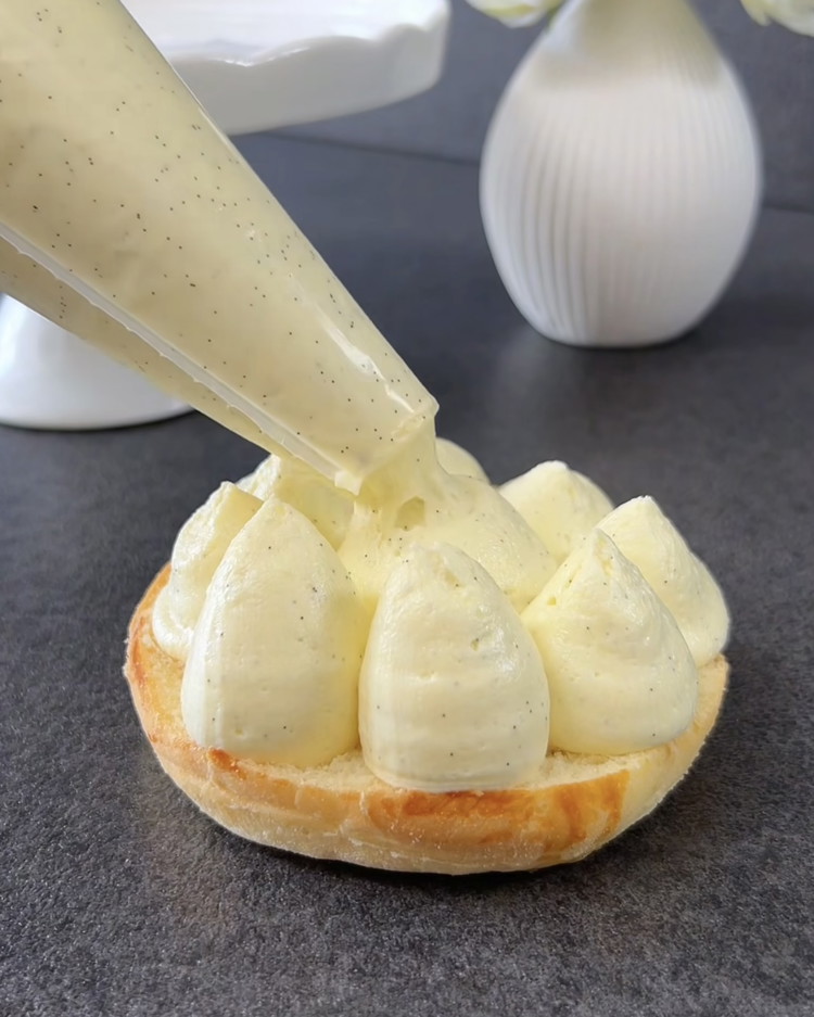 Image of Cut the cooled pastries in half horizontally. Pipe the crème mousseline onto the bottom halves and place the top halves back on. Dust with powdered sugar and serve.