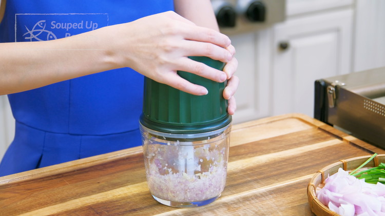 Image of Add half of the ginger slices, 2 garlic cloves, and 1 shallot into a blender and blend until finely minced.