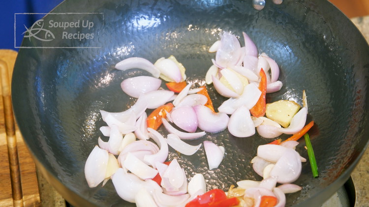Image of Turn the heat to high and heat the wok until smoking hot. Add a drizzle of oil, ginger slices, garlic slices, shallot, and red chili pepper. Stir for a minute or until fragrant.