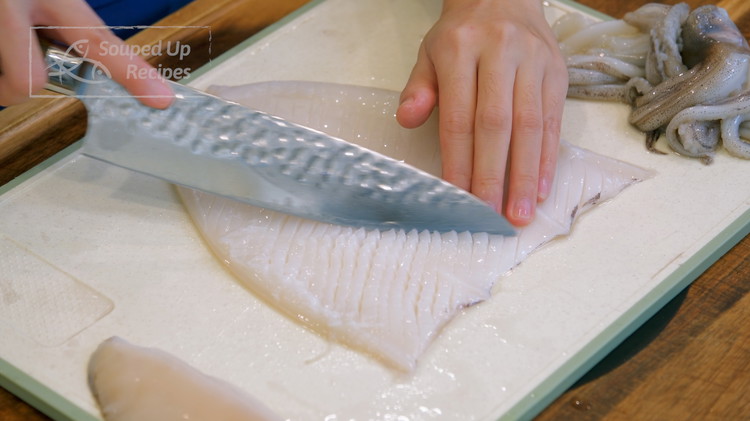 Image of Tear the fins off. Slice the squid hood lengthwise. Open it so the inside of the tube is facing up. If you see any messy tissues, clean it. Use a sharp knife to carefully create parallel diagonal lines that are...