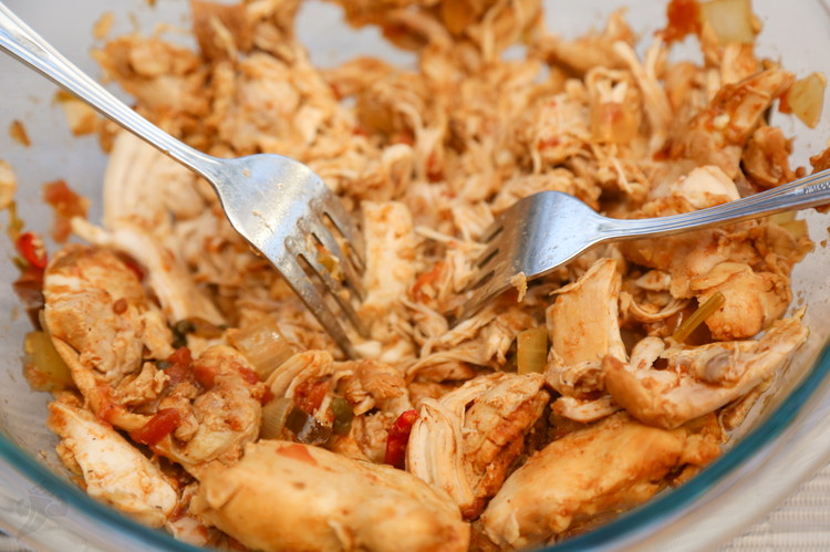 Image of remove chicken when it shreds easily, remove to another bowl and shred with 2 forks.