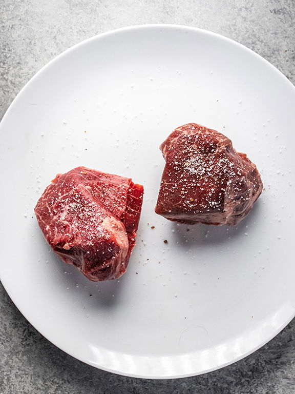 Image of Blot excess moisture from steaks with paper towel and season...