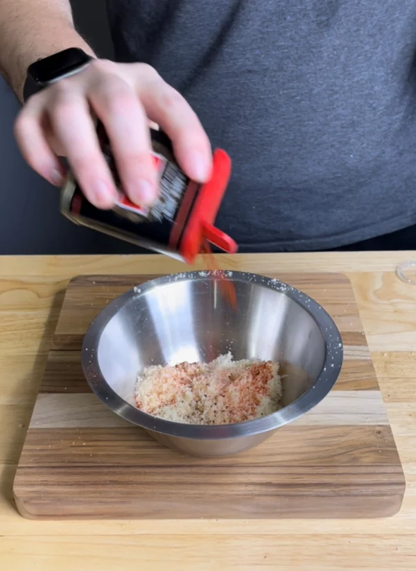 Image of In a large bowl, mix together the parmesan cheese, a tablespoon of salt, a teaspoon of pepper, and a pinch of smoked paprika.