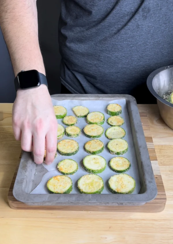 Image of Place your dried zucchini into a bowl and drizzle olive oil all over the slices. Take your Parmesan mixture and dump it on top. Make sure every chip gets plenty of seasoning!