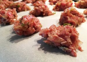 Image of PREPARA LE PORZIONI DEL COMPOSTO DI CARNE: Stendi un foglio di carta da forno e fai 24 porzioni uguali di carne macinata. Semplificati le cose e usa una bilancia. Nel nostro caso, il peso del ripieno complessivo era di 410...