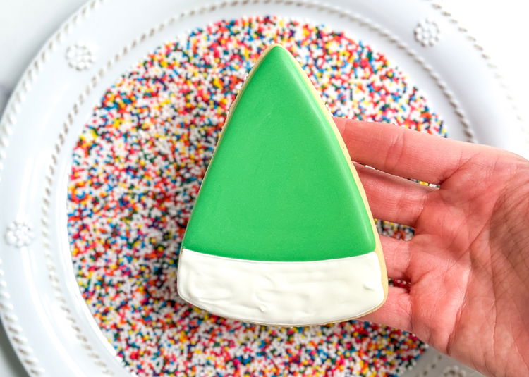 Image of Carefully pick up the cookie and dip it into the sprinkles, making sure you cover the entire area of white icing with sprinkles. You can pick up the cookie to check and dip again as needed. Make sure to dip the sides as well.  