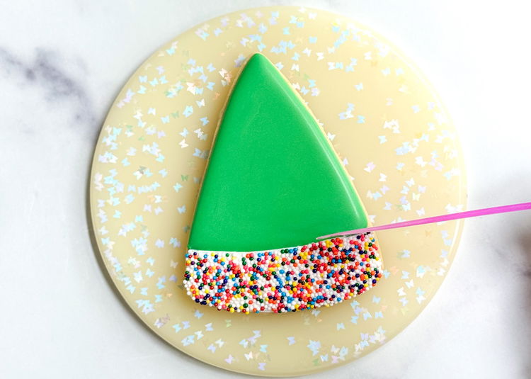 Image of Using your small spatula or spoon, carefully tap the top and sides of the sprinkles, ensuring you have clean lines of this section. You can also use your scribe tool or a toothpick to move the sprinkles around to ensure full coverage. 