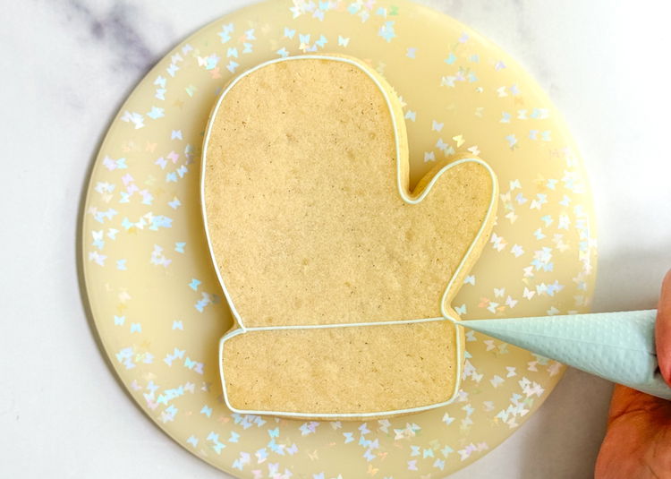 Image of Using the light blue outline consistency icing, outline the cookie as shown in the photo.   