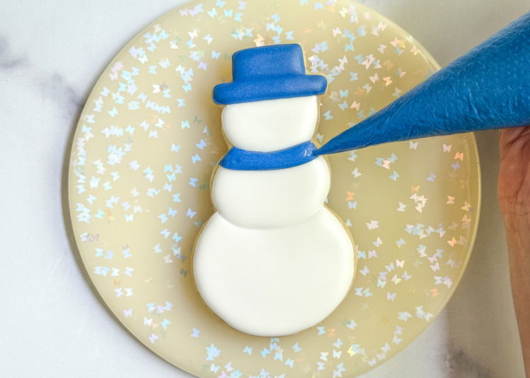 Image of Fill in the scarf shape you just outlined with the royal blue flood consistency icing. Settle the icing with your scribe tool or toothpick, and pop any air bubbles.