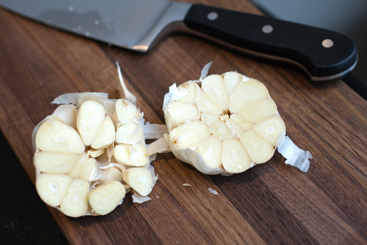 Image of cut the head of garlic in half so each clove is cut into two.