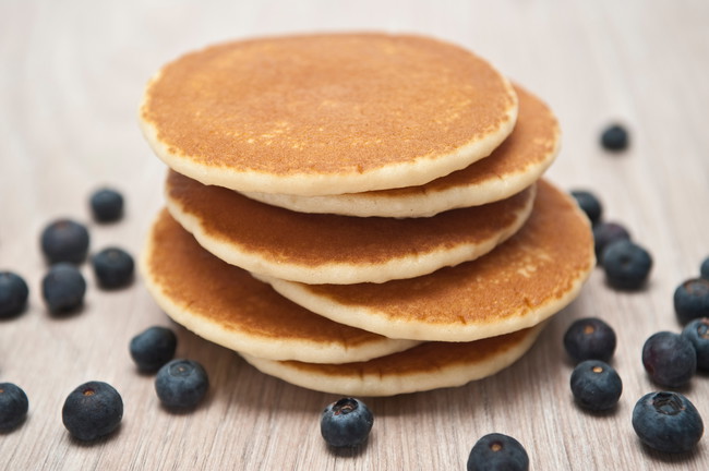 Stacked pancakes surrounded with blueberries