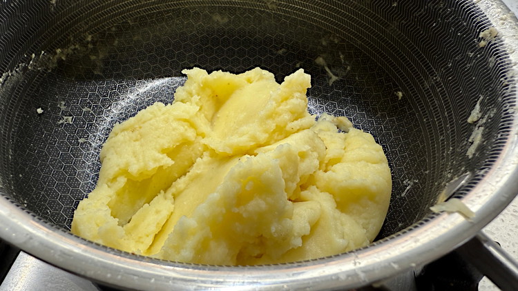 Image of pass spuds through a ricer, then mix in pepper and butter. Keep the pot in a warm place, or on your lowest heat setting