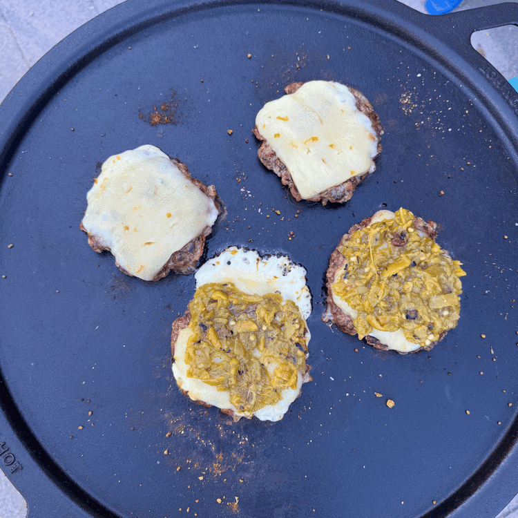 Image of Top with cheese slices. Melt the cheese. Add diced green chiles on top of two of the patties.