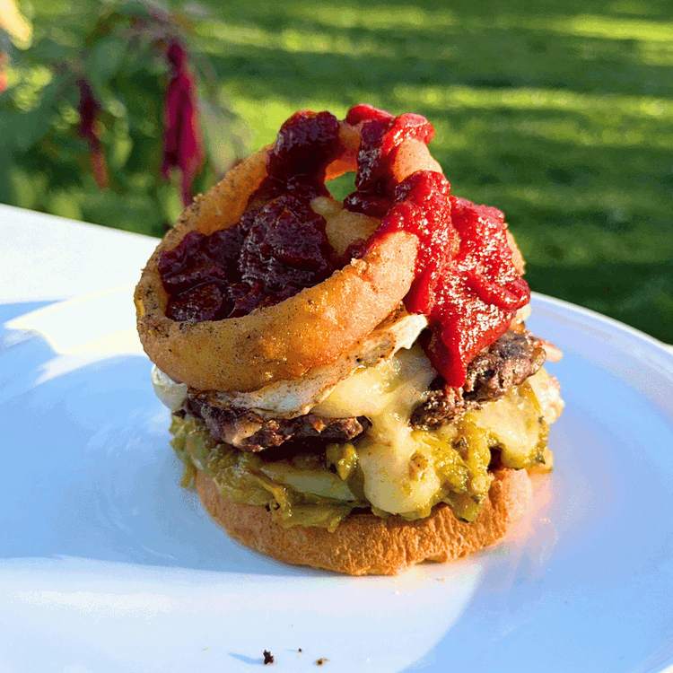 Image of Begin assembling the burgers. Spread mustard on the inside of the buns. Layer the patties, egg, and onion rings on top of the bottom bun. Drizzle BBQ sauce on top of the onion rings. 