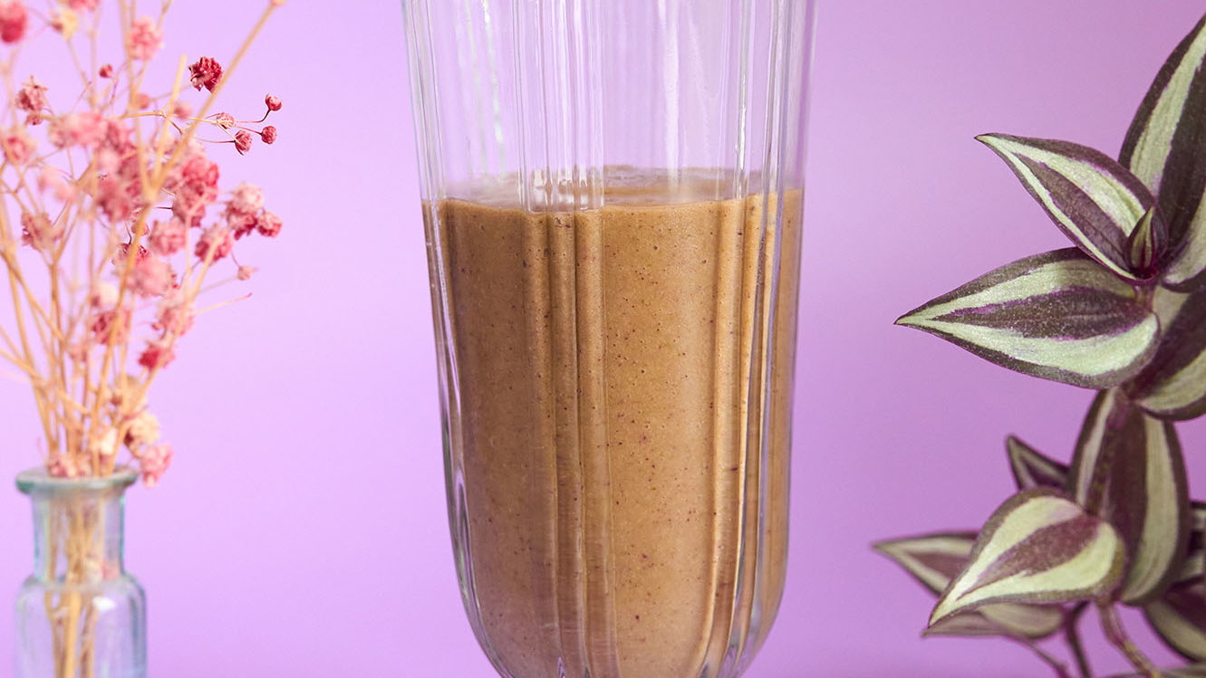A beige smoothie in a tall glass.