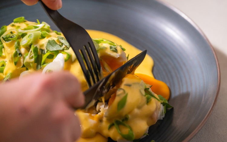 Image of Das Sauerteigbrot toasten oder in der Fischbutter anrösten. Darauf den Salat und die Fisch-Vinaigrette geben. Zwei warme pochierte Eier darauf platzieren. Nun die Hollandaise darüber löffeln und mit Frühlingszwiebelstreifen und Estragonstreifen bestreuen.