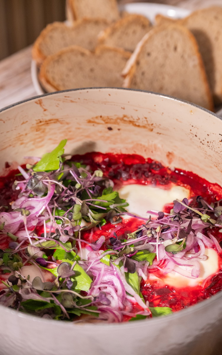 Image of Die Shakshuka aus dem Ofen nehmen und auf einem Teller anrichten. Kräuter, Kresse und fein gehobelte rote Zwiebeln mischen und dekorativ oben drauf drapieren. Bei Bedarf noch mit frisch gehobeltem Meerrettich servieren. Mit frisch gebackenem oder noch warmen Röstbrot servieren.