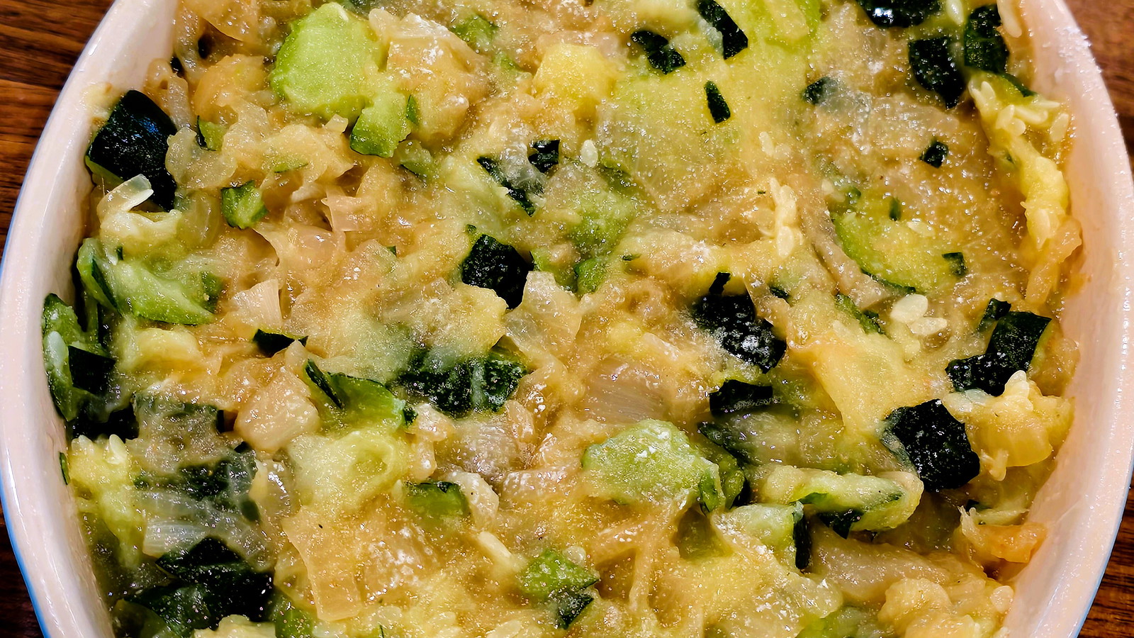 Image of green zucchini casserole with white cheese on top.